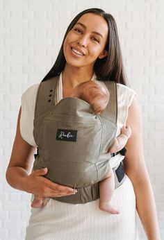 a woman holding a baby in a grey carrier