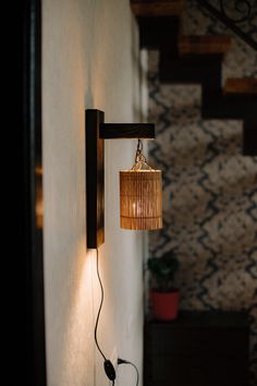 a wall mounted light with a lamp hanging from it's side next to a stair case