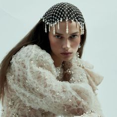 a woman with long hair wearing a white dress and headdress is posing for the camera