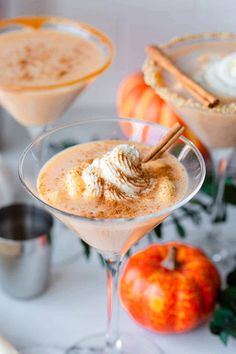 two glasses filled with pumpkin pie martinis on a table next to an apple and cinnamon stick