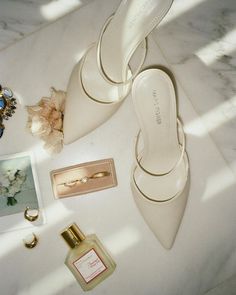 a pair of white high heels next to some jewelry