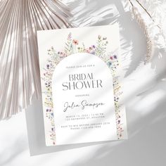 a white bridal shower card with flowers on it next to a fan and palm tree