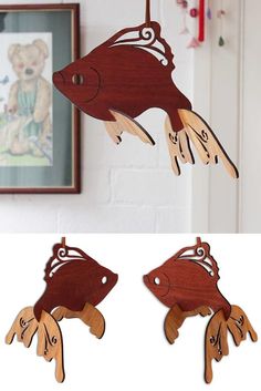 two wooden fish ornaments hanging from hooks on a wall next to a framed photo and an image of a teddy bear