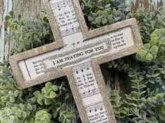 a wooden cross with sheet music on it and the words i am praying for you