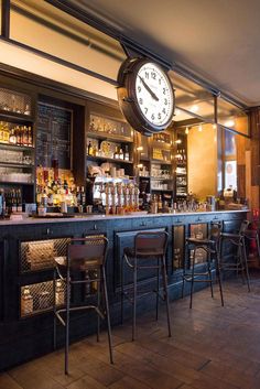 a bar with stools and a clock hanging from the ceiling