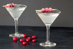 two martini glasses with cranberries on the rims and garnishes