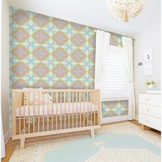 a baby's room with a crib, dresser and wallpaper in pastel colors