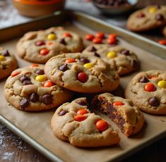 chocolate chip cookies with candy corn and m & m's are on a baking sheet