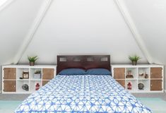 a bed sitting under a white roof next to a book shelf filled with books and plants