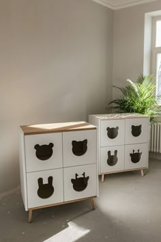 two white drawers with black handles in front of a potted plant on the floor