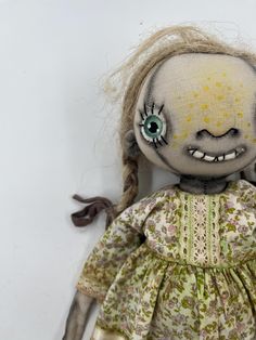 a creepy doll with green eyes and long hair wearing a yellow dress on a white background