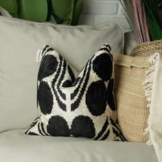 a black and white pillow sitting on top of a couch next to a potted plant