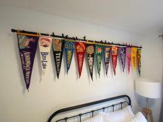 there are many pennants hanging on the wall above the headboard in this bedroom