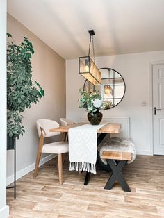 a dining room table with chairs and a bench in front of the mirror on the wall