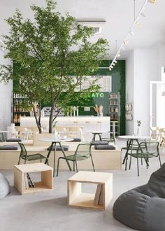 an empty room with tables and chairs in front of a green tree on the wall