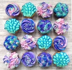 cupcakes decorated with blue, pink and purple icing are arranged in rows