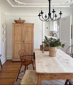 a wooden table sitting in the middle of a living room next to a tall cabinet