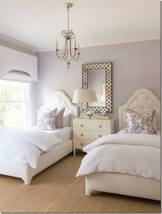 two white beds sitting next to each other in a bedroom under a chandelier