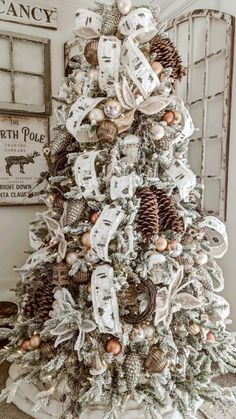 a white christmas tree decorated with pine cones and ribbons