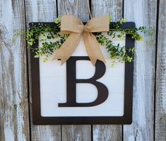 a wooden sign with the letter b hanging from it's side on a fence