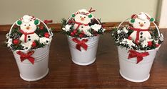 three snowmen are sitting in buckets decorated with christmas decorations