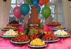 a table topped with lots of different types of food and balloons in the air above it