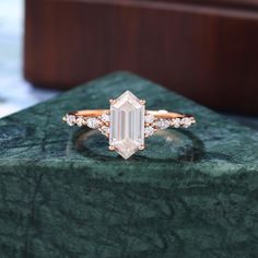 an emerald colored diamond ring sitting on top of a green marble slab