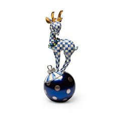 a blue and white figurine sitting on top of a black ball with gold horns