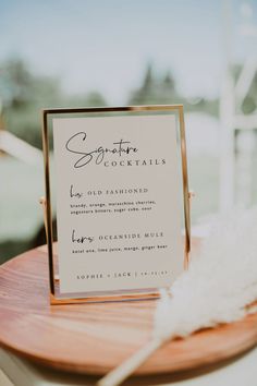 a close up of a sign on a table with a white feather in front of it