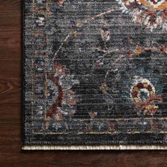 an area rug with various colors and designs on the floor in front of a wooden wall