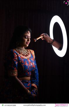 a woman getting her makeup done by a man in a dark room with the word o on it