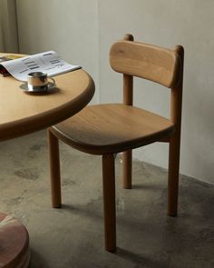 a wooden chair sitting in front of a table with a cup on top of it