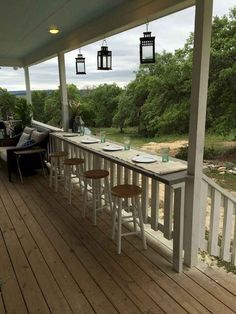 an outdoor dining area with wooden floors and white railings on the side of a house