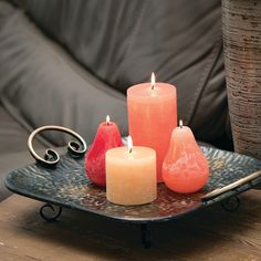 three candles sitting on a tray next to a potted plant