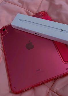 two red ipads sitting next to each other on top of a pink sheet covered bed