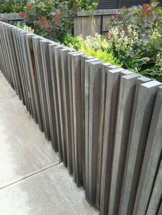 a wooden fence with plants growing on it's sides in front of a building