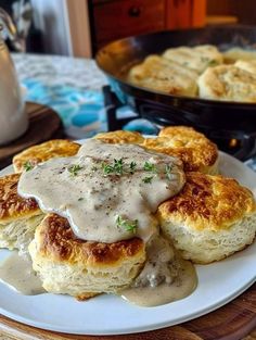 biscuits and gravy on a white plate with a serving dish in the background