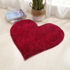 a red heart shaped rug next to a potted plant