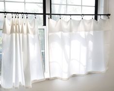 two white curtains are hanging in front of a window