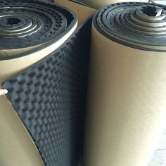 several rolls of black and tan colored rubber flooring on top of eachother