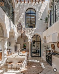 an indoor kitchen and dining area with white walls, arched doorways, and stone flooring