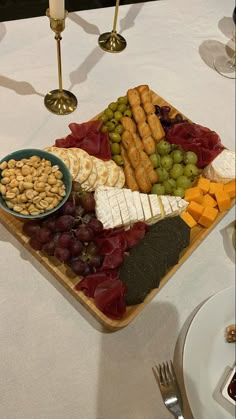 a platter of cheese, crackers, grapes and nuts on a dining table