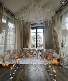 a room filled with lots of white balloons and candles on top of a wooden floor