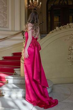 a woman in a pink dress is standing on the stairs with her back to the camera