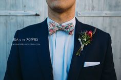 a man in a suit and bow tie with flowers on his lapel flower boutonniere