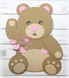 a brown teddy bear with pink hearts on it's chest sitting on a white wooden surface