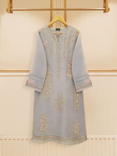 grey embroidered organza straight shirt crafted with utmost care and attention to detail. The shirt features intricate embroidery on the front and sleeves, adding a touch of timeless charm. Paired with a matching pant Length: 46" Pants Fabric: Raw Silk Elegant Gray Kurta For Eid, Gray Kurta For Wedding And Eid, Elegant Gray Designer Wear Sets, Gray Resham Embroidery Kurta For Wedding, Gray Embroidered Kurta For Eid, Elegant Gray Kurta With Resham Embroidery, Embroidered Gray Kurta For Eid, Gray Traditional Sets With Chikankari Embroidery, Traditional Gray Chikankari Embroidery Sets