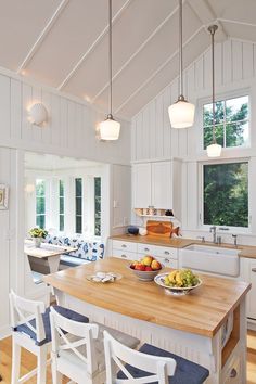 a large kitchen with white cabinets and wooden counter tops, along with blue cushions on the chairs