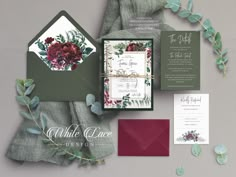 the wedding stationery is laid out with flowers and greenery on it, along with matching envelopes