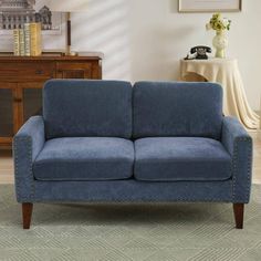 a blue couch sitting in a living room next to a table and lamp on top of a rug